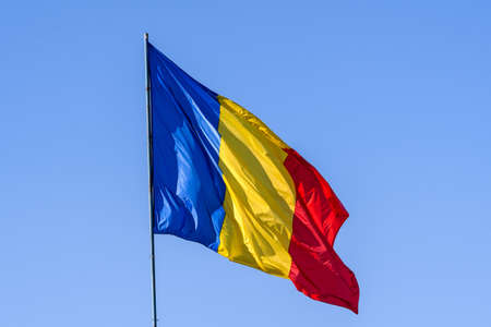 Romanian national flag blowing in the wind in direct sunlight towards clear blue skyの写真素材