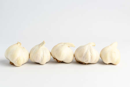 Fresh organic garlic on a white table, isolated on white background with soft focus, side view of tasty healthy vegan foodの写真素材
