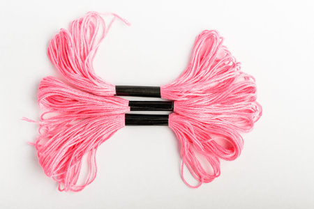 Three vivid pink sewing threads for embroidery isolated on a white table, top view or flat lay of...