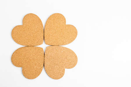 Shape with four hearts made from light brown textured cardboard, isolated on white with space for textの写真素材