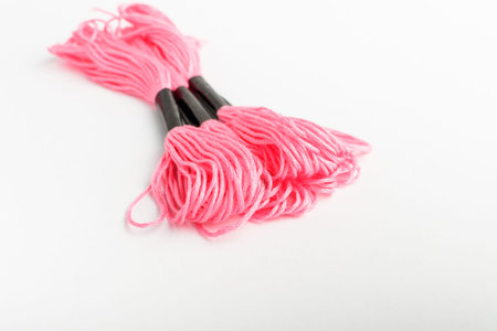 Three vivid pink sewing threads for embroidery isolated on a white table, top view or flat lay of...