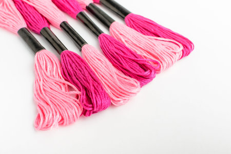 Six mixed vivid pink sewing threads for embroidery isolated on a white table, top view or flat lay of textile materialsの写真素材