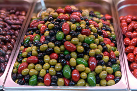 Fresh organic red, green, yellow and black olives displayed for sale at Naschmarkt a street food market in Vienna, Austria, healthy Greek vegan food photographed with soft focusの写真素材
