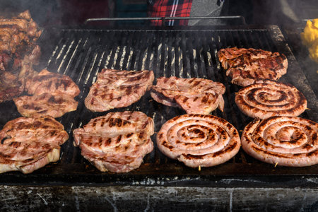 Mixed meat sausages being cooked on a hot black metallic grill in display for sale at a restaurant...