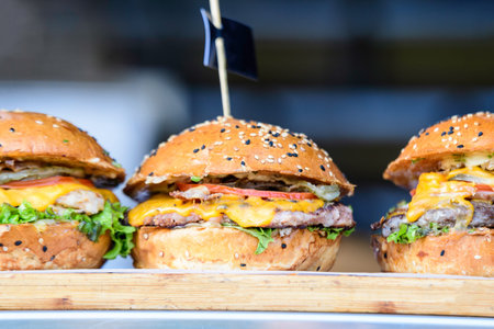 One fresh healthy sandwich or burger with ham, green salad and pickled cucumbers on a brown wooden...