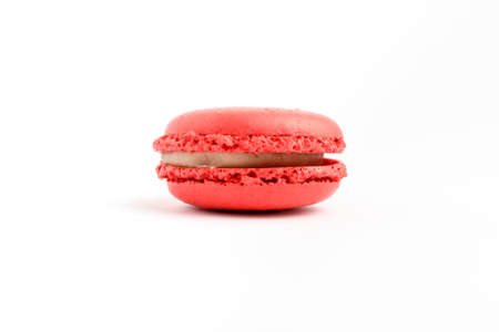 Side view of one sweet vivid red strawberries French macaron isolated on white background, tasty French dessert on a tableの写真素材