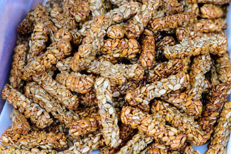 Fresh home backed crispy crackers with sun seeds and honey in direct sun light, displayed for sale at a bakery at a street food market festivalの写真素材
