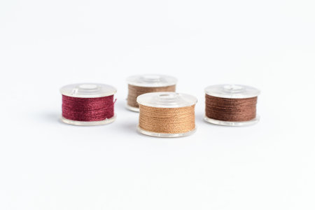 Different spools of mixed beige and brown cotton thread prepared for sewing machine, isolated on...