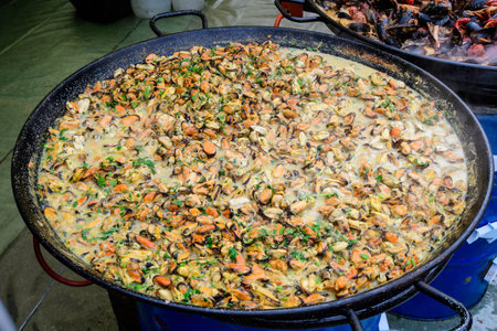 Large group of cooked mussels with tomato and cream sauce at a street food festival, ready to eat seafood,  beautiful orange monochrome outdoor backgroundの写真素材