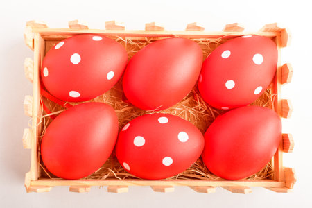 Decorative red Easter eggs in a small wooden box isolated on a white tableの写真素材