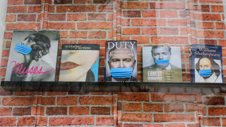 Bucharest, Romania - June 6, 2020: Four medical protection masks are added on books behind a store window closed down in order to mitigate the spread of the Coronavirus (COVID-19) outbreakのeditorial素材