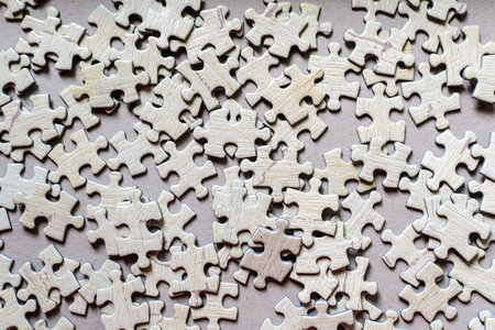 Many light grey textured cardboard puzzle pieces on a table, weekend indoor activity for playing with children at homeの写真素材