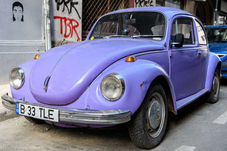 Bucharest, Romania, 9 February 2019 Old vivid mauve Volkswagen Beetle car parked a street in a sunny dayのeditorial素材