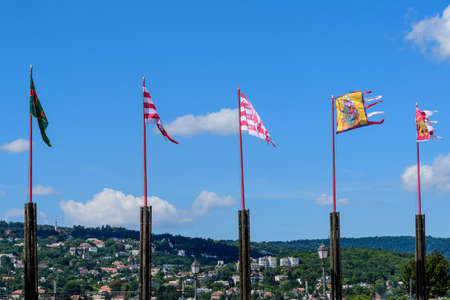 Many vivid colorful flag blowing in the wind in direct sunlight towards clear blue sky in a sunny day near the Buda Castle in Budapest, Hungaryの写真素材