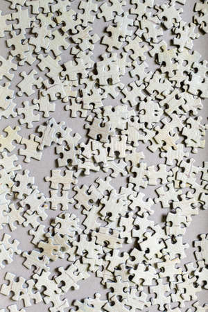 Many light grey textured cardboard puzzle pieces on a table, weekend indoor activity for playing with children at homeの写真素材
