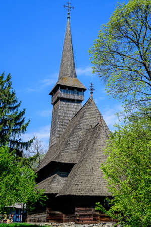 Bucharest, Romania - 25 April 2021: Old traditional Romanian church surounded with many old trees and green grass in Dimitrie Gusti National Village Museum in Herastrau Park in a sunny spring dayのeditorial素材