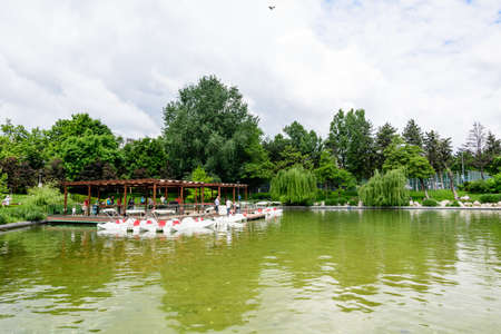 Bucharest, Romania - 29 May 2021: Landscape with lake and vivid green trees in Drumul Taberei Park (Parcul Drumul Taberei) also known as Moghioros Park, in Bucharest, Romania, in a cloudy summer dayのeditorial素材
