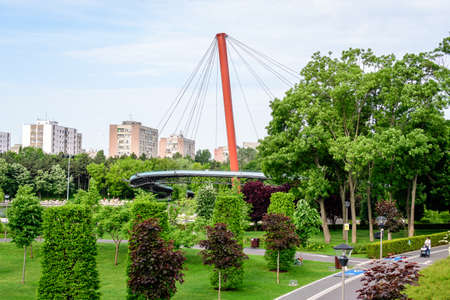 Bucharest, Romania - 25 May 2021: Landscape with the modern metallic bridge, lake and green trees in Drumul Taberei Park (Parcul Drumul Taberei) also known as Moghioros Park, in a cloudy summer dayのeditorial素材