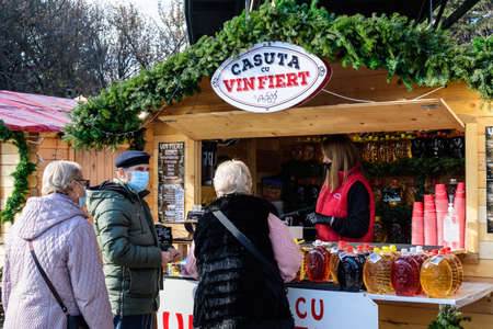 Bucharest, Romania - 28 November 2021: People enjoying traditional hod drinks, food and sweets at Christmas Market in Drumul Taberei Park (Parcul Drumul Taberei) known as Moghioros, in a sunny dayのeditorial素材