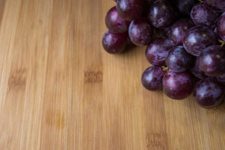 Bunch of red grapes on top of a wooden boardの写真素材