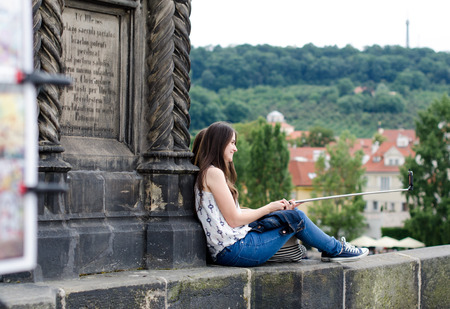 Prague, Czech Republic - June 26: The girl sit on the Charles Bridge and take the selfie on June 26, 2015 in Prague, Czech Republic.のeditorial素材