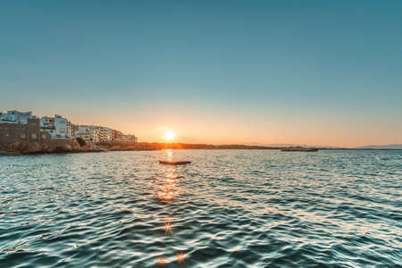 Sunset on the beach with sun rays reflected in the waterの写真素材