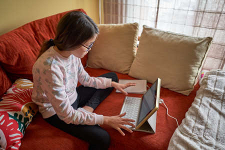 Girl studying at home with laptop in confinement for coronavirusの写真素材