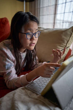 Girl studying at home with laptop in confinement for coronavirusの写真素材