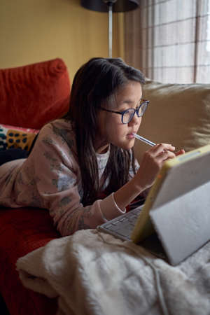 Girl studying at home with laptop in confinement for coronavirusの写真素材