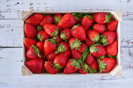 Deep red strawberries picked in a farmer wooden box on white wooden tableの写真素材