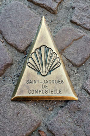 Mark in the form of a metal triangle on the ground indicating the way to Santiago de Compostela in Saint jean Pied du Portのeditorial素材