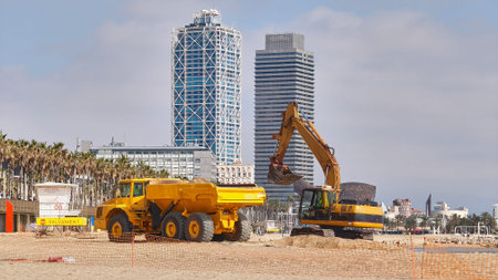 Excavator and dump truck working on beach restoration and sand replenishment on an urban beach in Barcelona, Spain. Heavy construction machinery repairing coastal erosion on the Meの写真素材