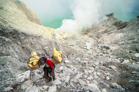 Worker at Kawah Ijen sulfer mine carries a basket of sulfur out of the craterのeditorial素材