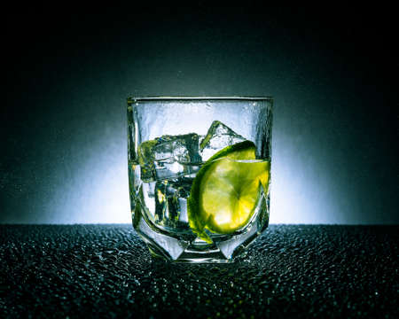 Gin and tonic with ice and lime on a dark background with white spot Gin and tonic with ice and lime on a dark background with white spot