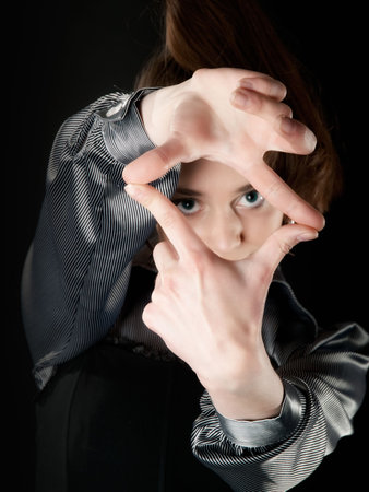 Young girl making frame with her fingers indark with bluring faceの写真素材