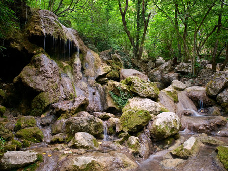 Small waterfalls surrounded by rocks and vegetationの写真素材