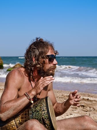 Man drum on tam-tam on the beach の写真素材