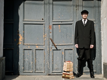 young man in vintage style is standing against the old doorの写真素材