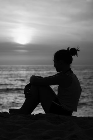 Silhouette of girl on the seashore at sunset. Black and whiteの写真素材