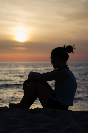 Silhouette of girl on the seashore at sunset.の写真素材