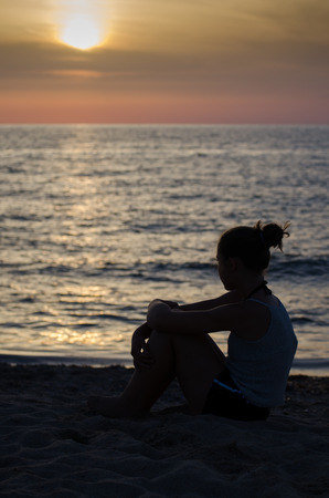 Silhouette of girl on the seashore at sunset.の写真素材