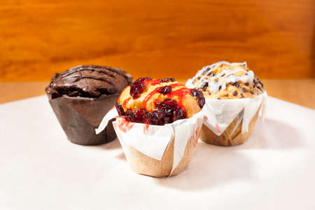 Three muffins on a wooden cutting board.の写真素材
