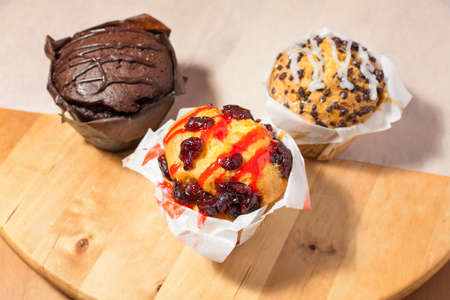 Three muffins on a wooden cutting board.の写真素材
