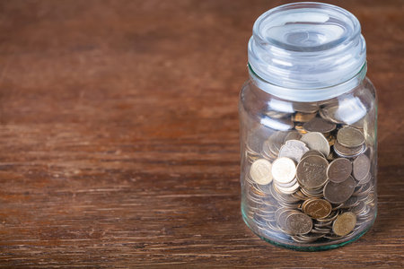 Jar savings spare change concept dark wood background.