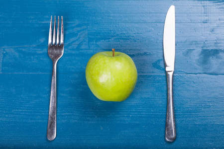 Vintage old cutlery knife fork green healthy apple blue wood backgroundの写真素材