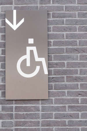disabled person and an arrow on a wall made of bricks.の写真素材