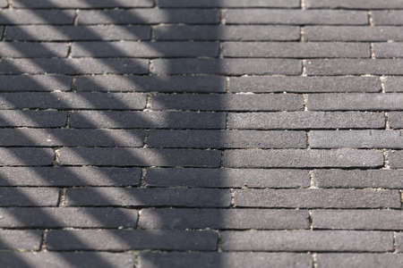 shadow on a pavement made of dark bricks.の写真素材