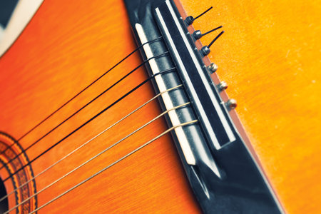 Bridge, strings and rose of a yellow and orange guitar. Musical instrument.の写真素材