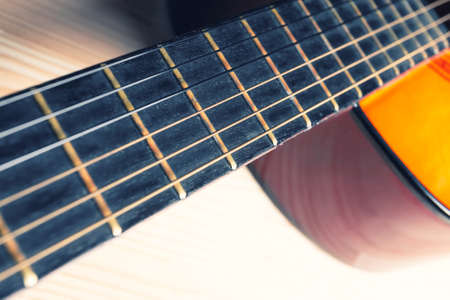 Neck, strings, sound box of a yellow and orange guitar. Music instrument. Light wooden background.の写真素材