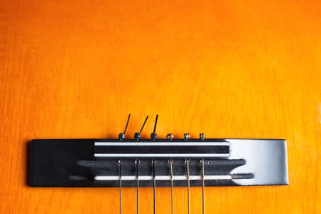 Bridge and strings of a yellow and orange guitar. Musical instrument. Copy space at the top.の写真素材